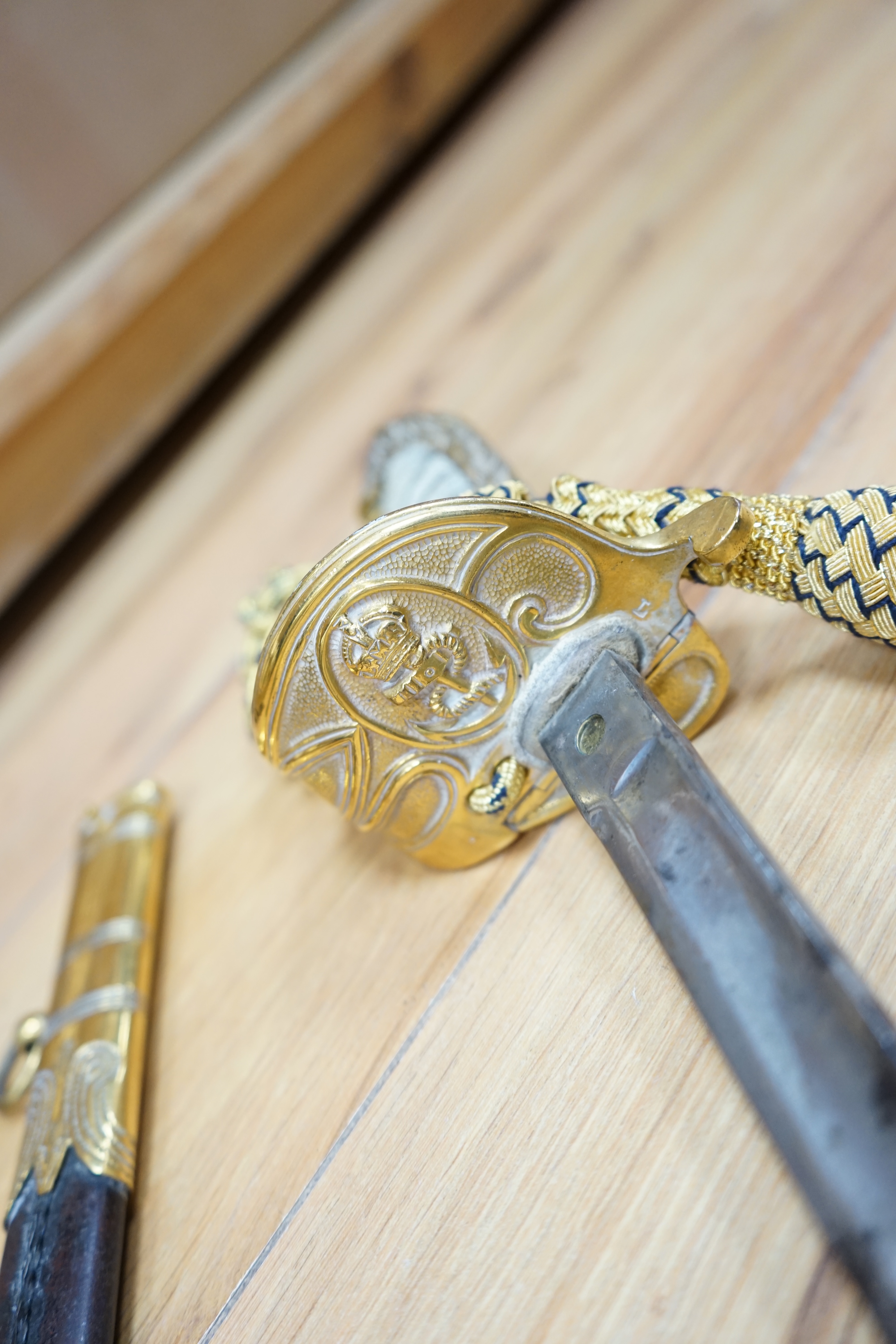 A Victorian Royal Navy officer’s sword by Grieves, engraved blade, lion’s head pommel, fish skin grip, folding guard engraved with R.J. Murray, with its sword knot and leather scabbard with brass mounts, blade 79cm. Cond